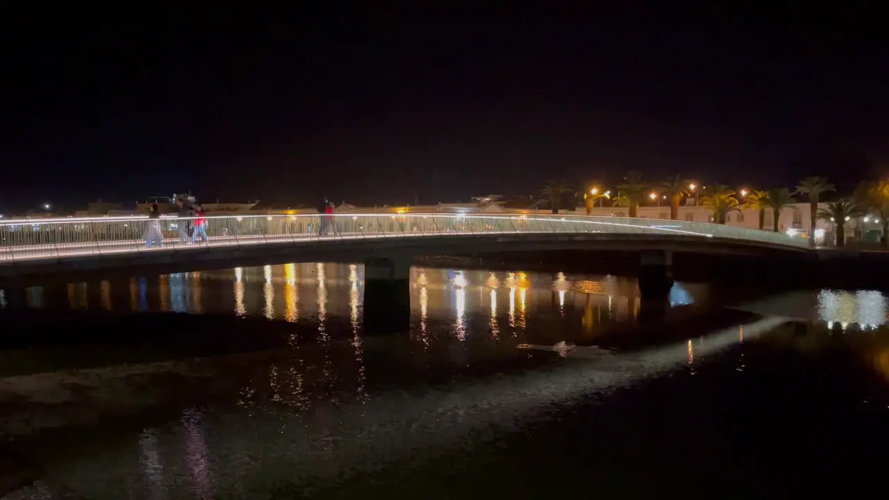 Beautifully lit pedestrian bridge over The river Galao in Tavira Portugal on a still warm spring night