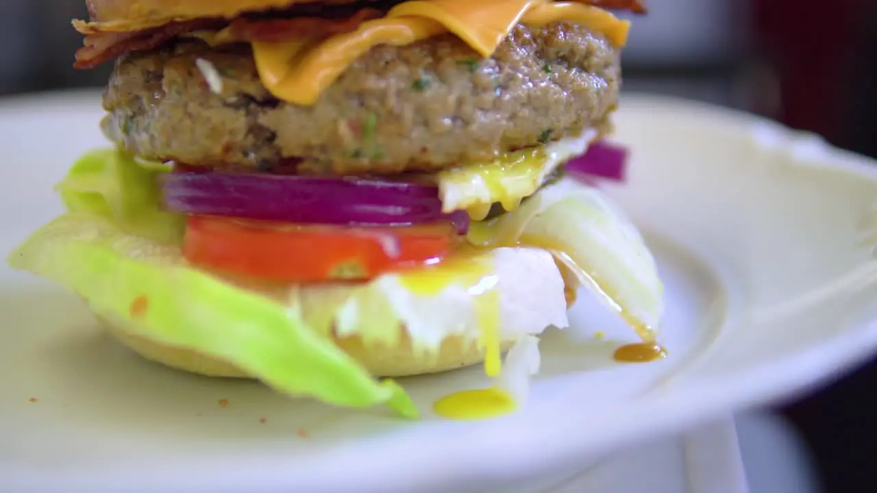 Ready to eat burger straight from the grill having egg flows down on the lettuce in slow motion