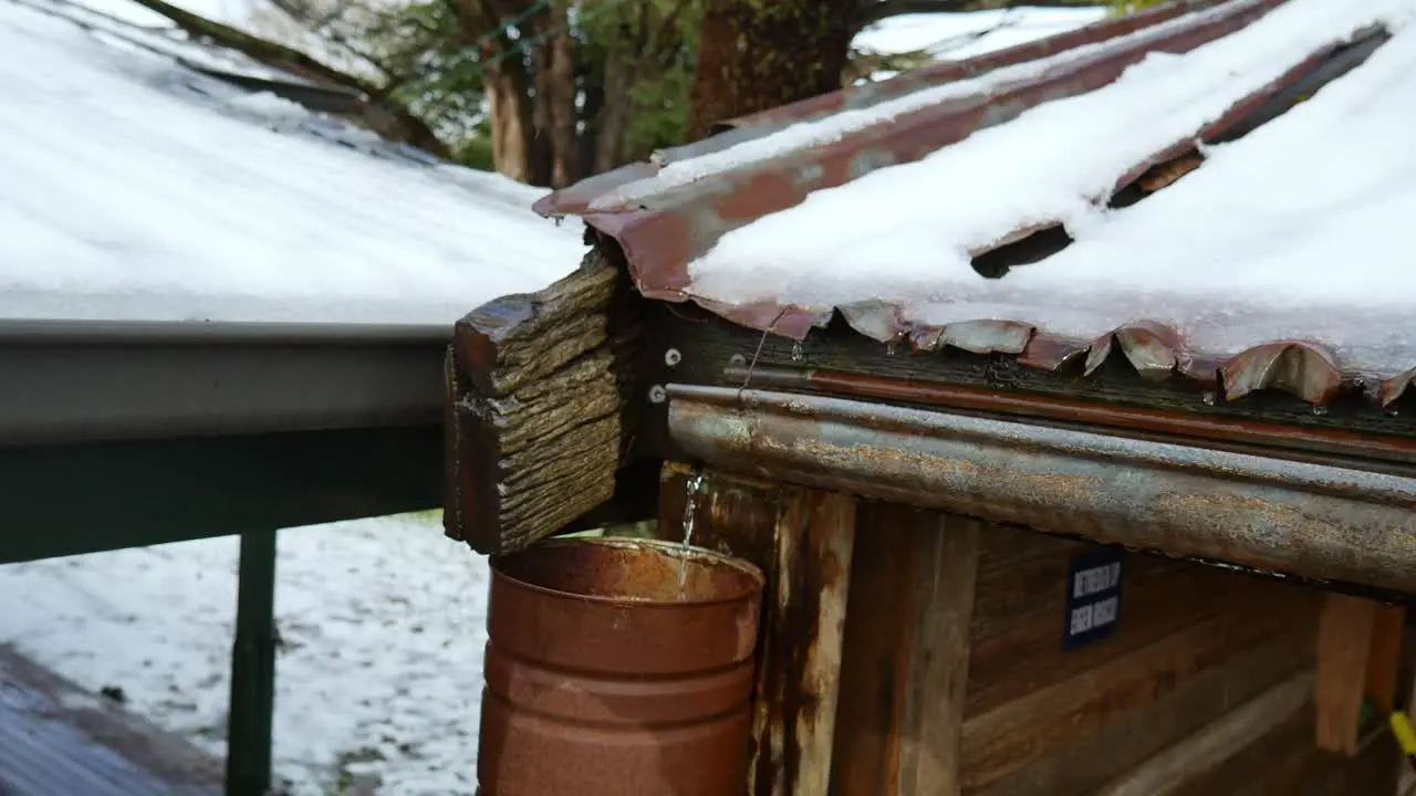 Water flowing from a an old gutter into a rustic downpipe on an old building during rain