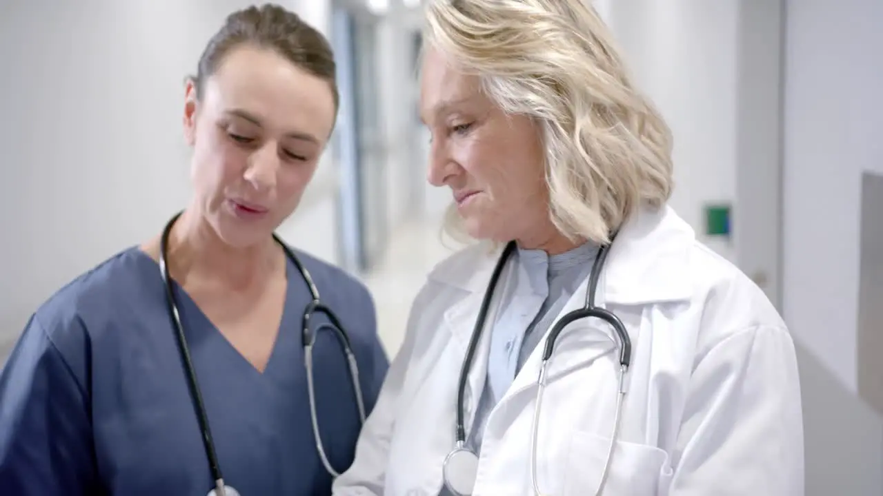 Caucasian female doctors in discussion in hospital corridor slow motion