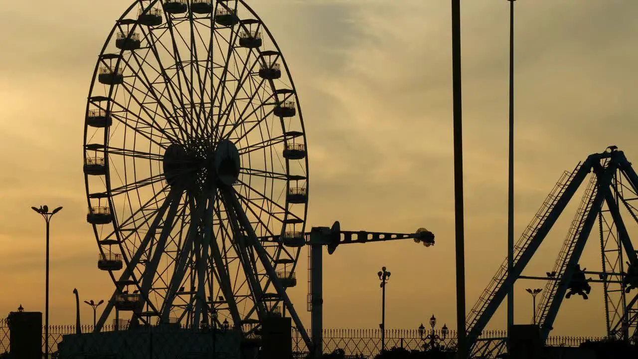 Amusement Park Ferris Wheel Silhouette Against Orange Sunset Sky