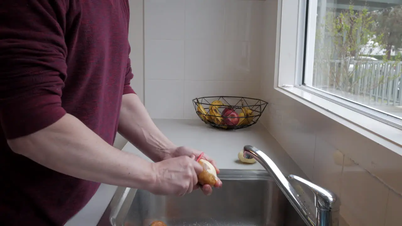 Man peeling potatoes at a kitchen sink