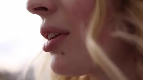 Extremely close up of woman's mouth eating fresh strawberry Beautiful female lips Blonde haired caucasian Side view