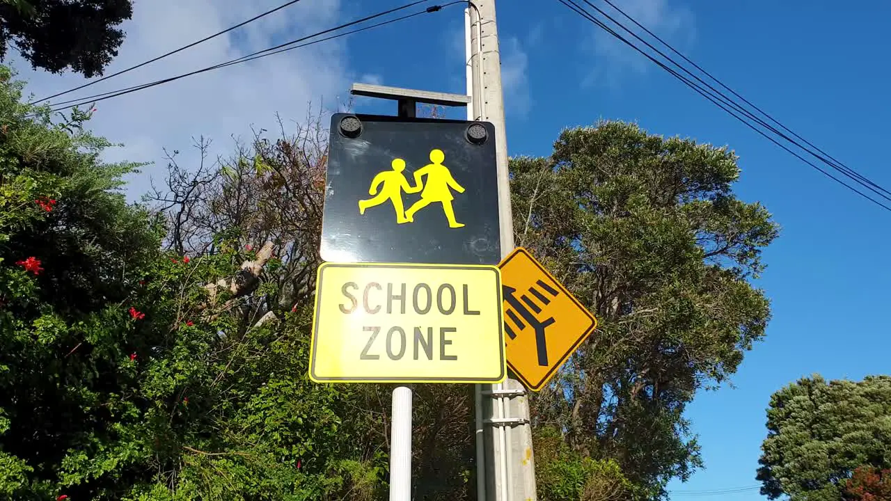 Caution school zone road sign with symbol of parent and child in New Zealand Aotearoa