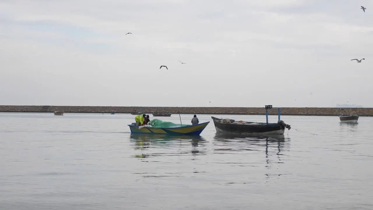 Small Fishing Boat Going Past With Seagulls Flying Overhead At Gwadar On Coast Of Balochistan