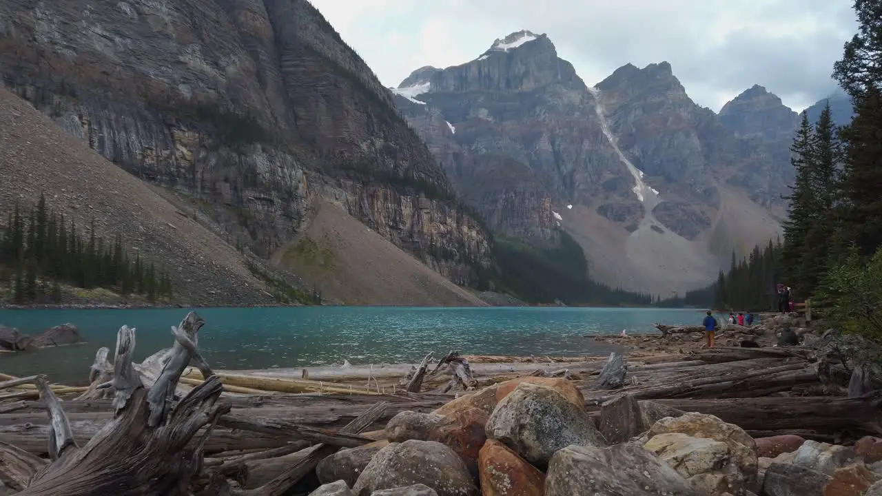 Moraine lake mountains with tourists Alberta Canada pan