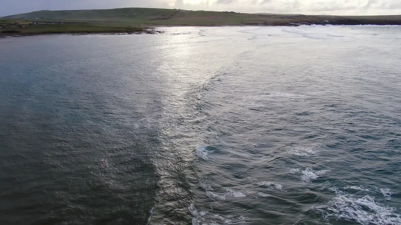 Slow motion aerial view of the North Sea waves while flying away from the sun