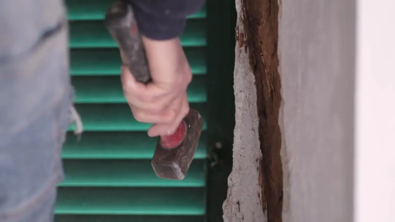 hammer smashing concrete from a wall