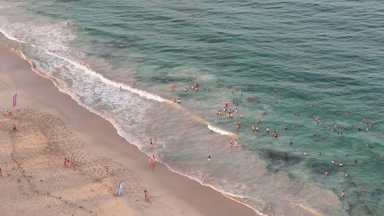 Group of people floating in the shallow ocean waters of beach at sunrise