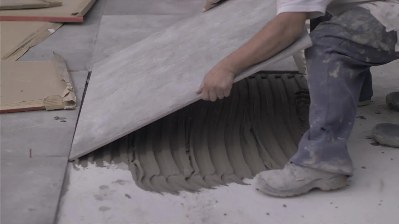 Man installing big ceramic floors on the outside of the home in 4k slowmotion