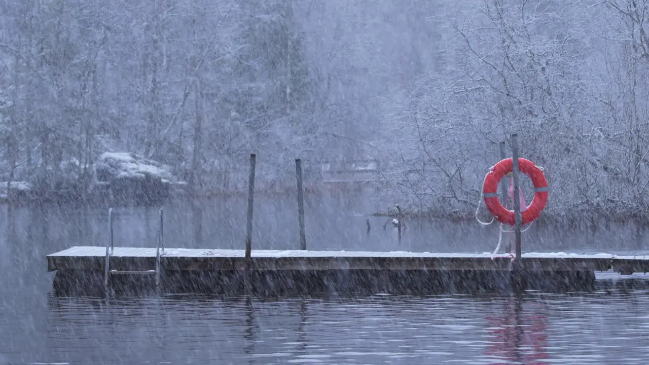 Heavy snowfall on a river with dock and lifebuoy tripod shot