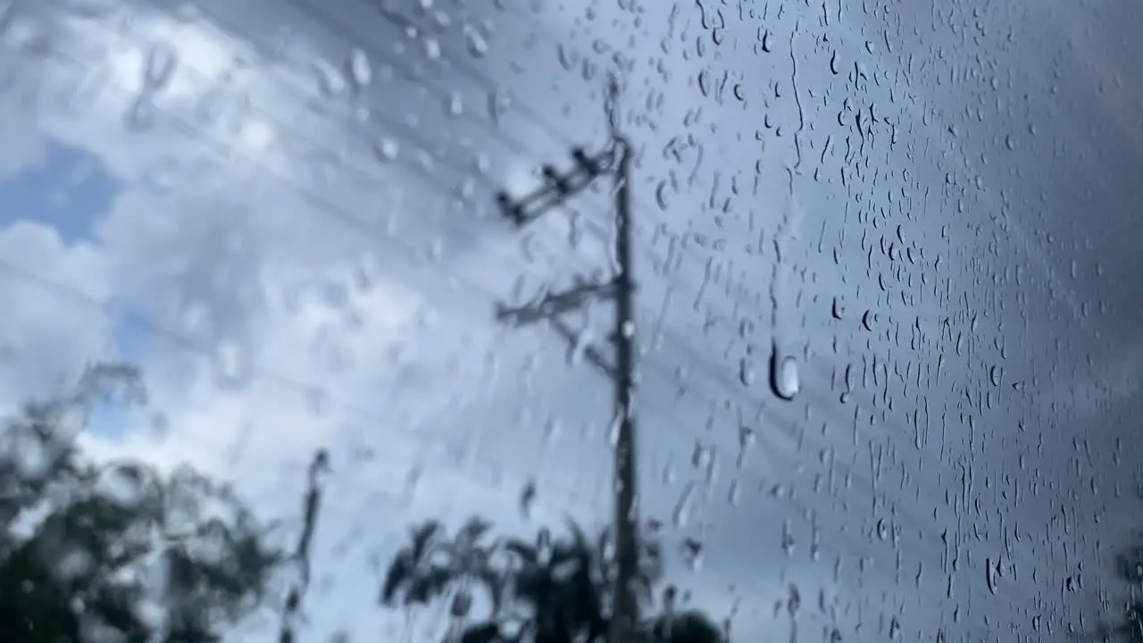 Point of view shot of raindrops on window glass after heavy rain with the blurred cloudy sky outside the window