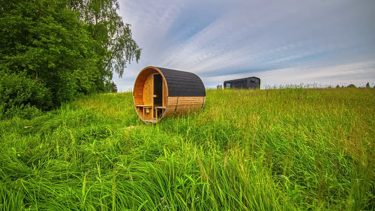 Summer landscape sunset time-lapse with sauna in a green meadow blue sky