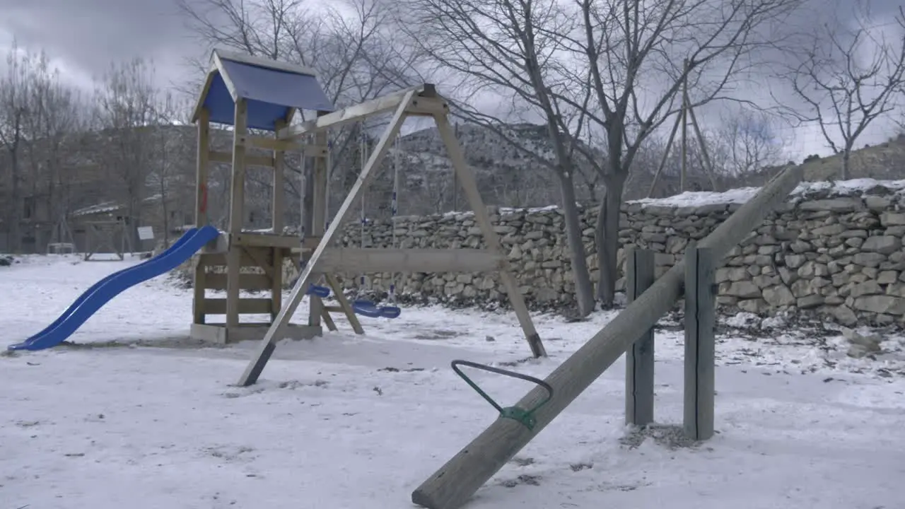 Empty kids playground with ice and snow around in the park