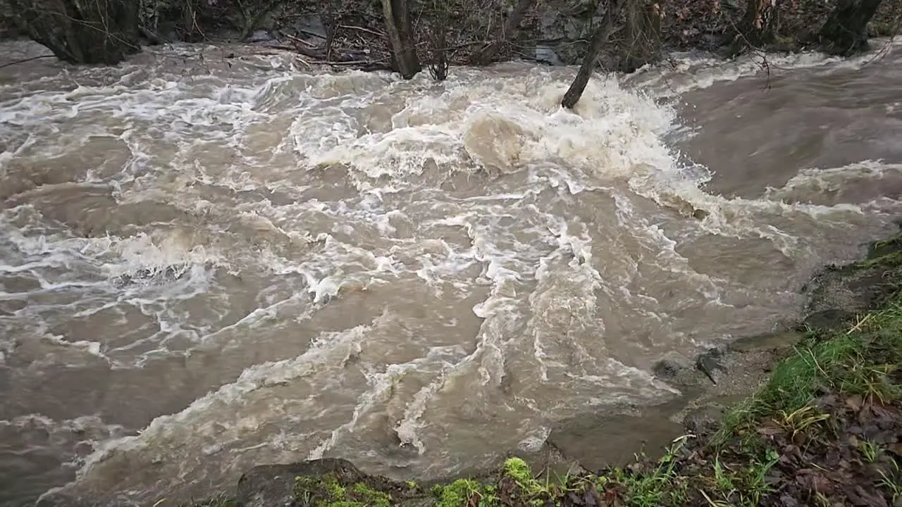 Dirty flood water flowing fast in the river abstract close-up super slow motion video