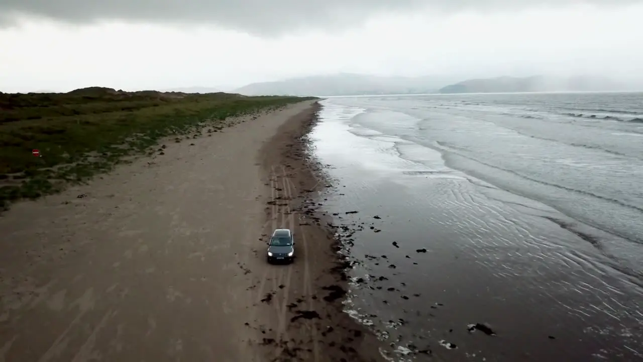 Drone view of a car driving on a huge Irish beach