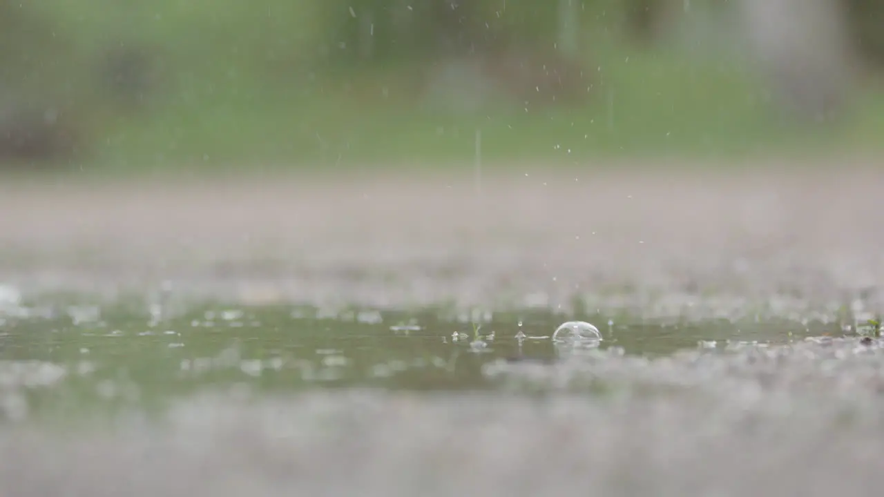 SLOW MOTION CLOSEUP Heavy rain droplets falling into a puddle