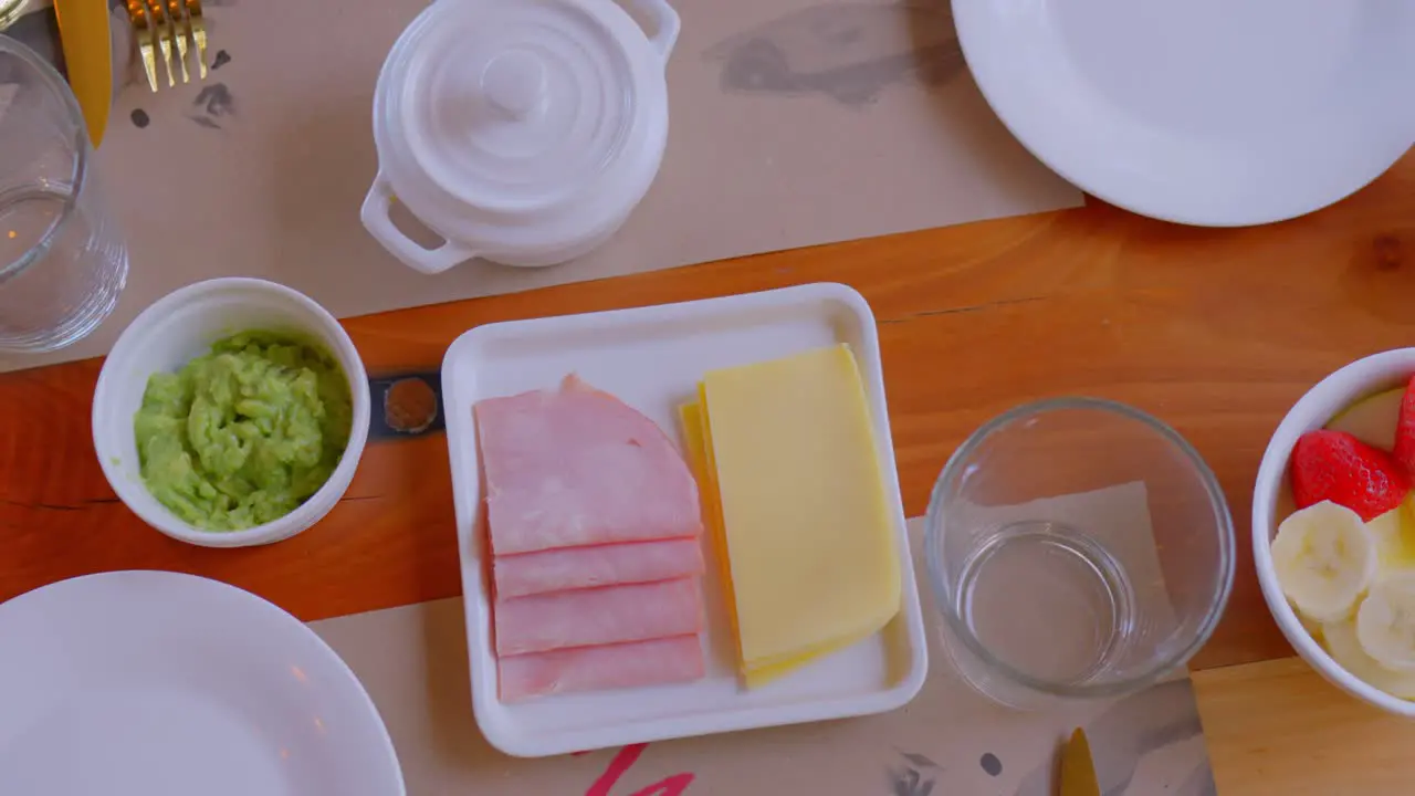 Table top view with breakfast served it can be seen that there is coffee fruits ham cheese and homemade bread