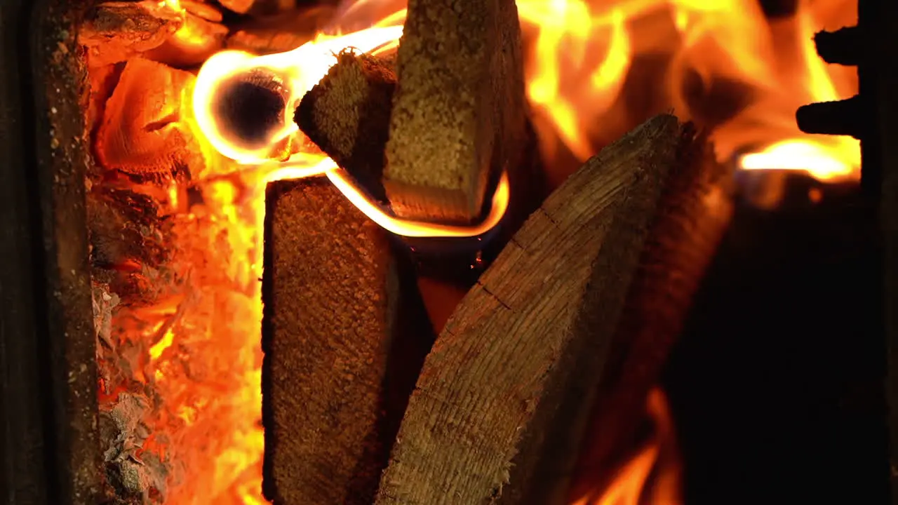 Fiery flame of burning firewood in domestic fireplace vertical close up view