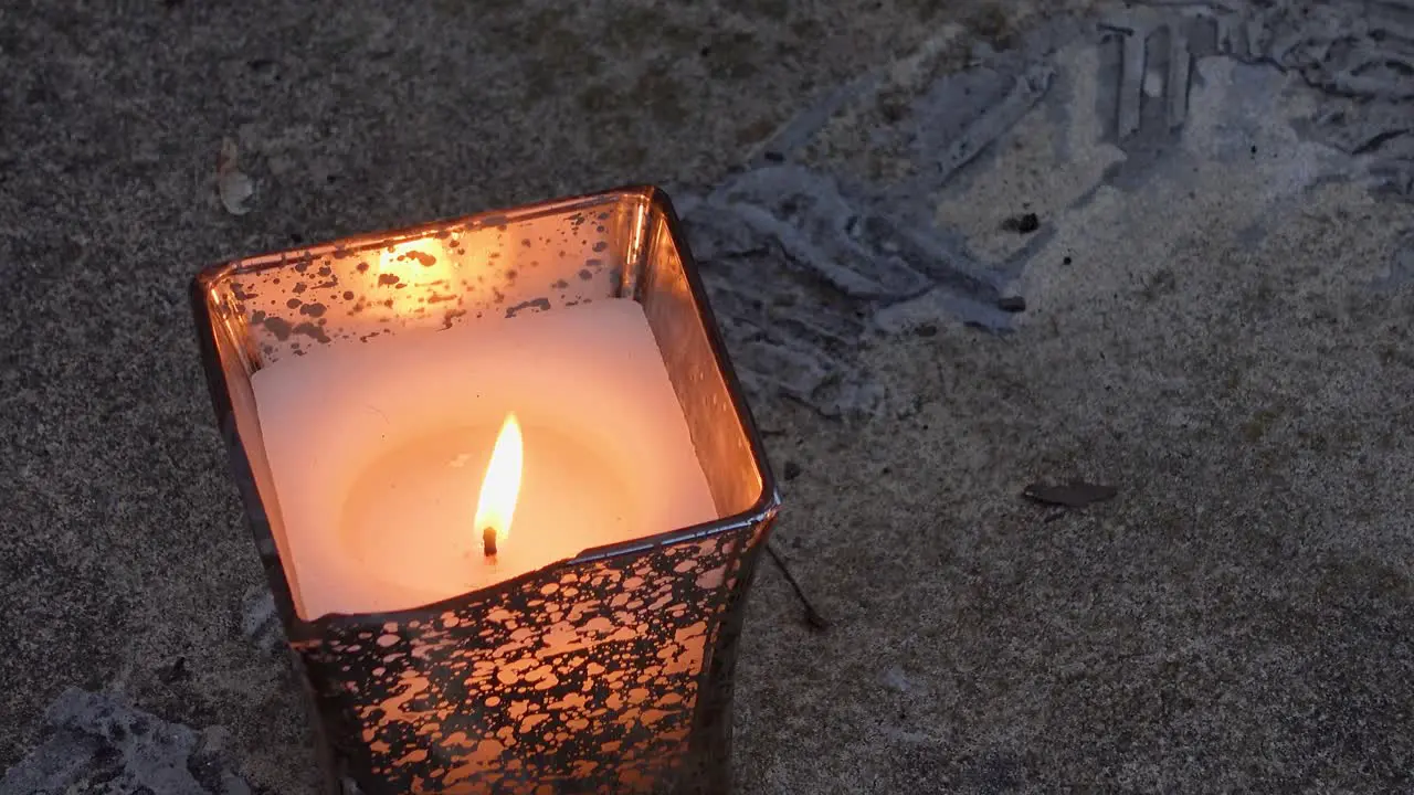 Single Lighted Candle In Metallic Can Waving Flame In Wind