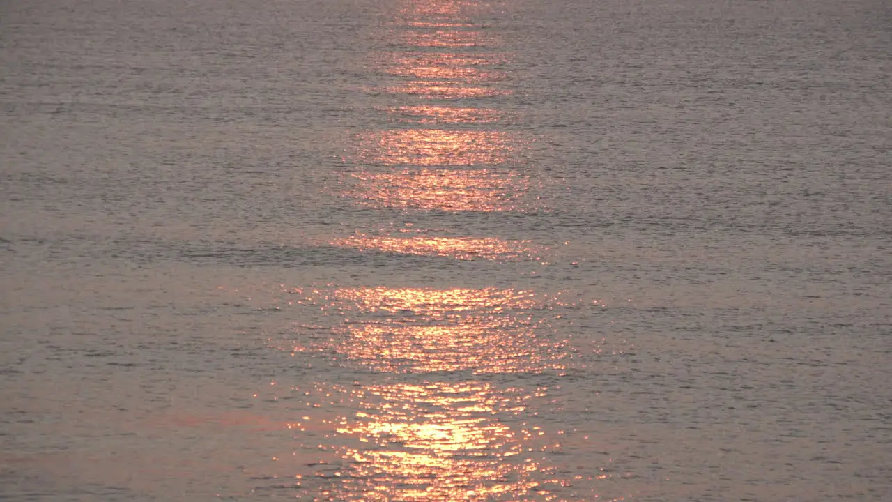 A stunning red and golden sunrise reflects on calm silvery waters as small waves roll in