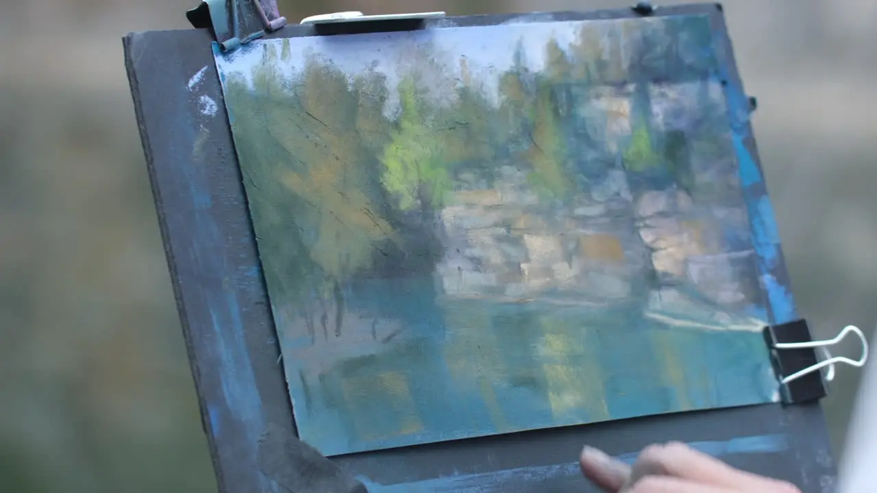 Close up footage of a women painting with pastels outside