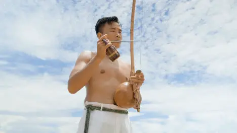 Shirtless man playing instrument