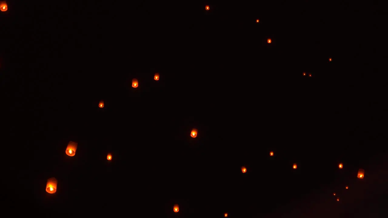 Traditional Thai lanterns floating in dark night sky