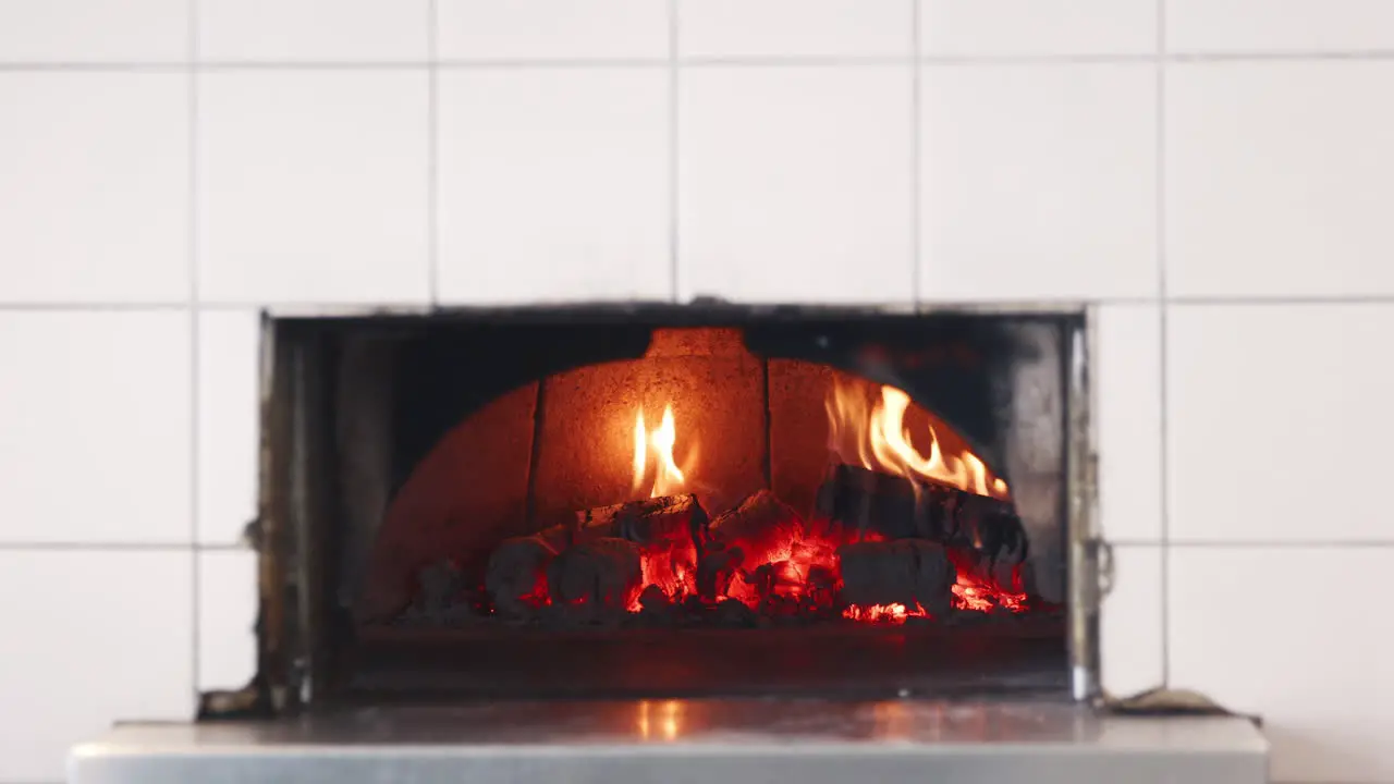 Flames and wood burning in the clay oven at an artisan bakery close up