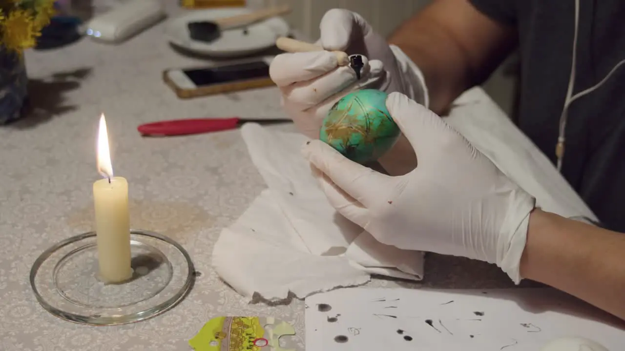 Female hands decorating an Easter egg using the traditional Ukrainian technique Pysanka using paints and wax