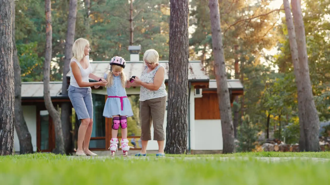 Mom And Grandmother Are Taught To Roller-Skate A Girl Of 6 Years Support Her By The Hand Concept T