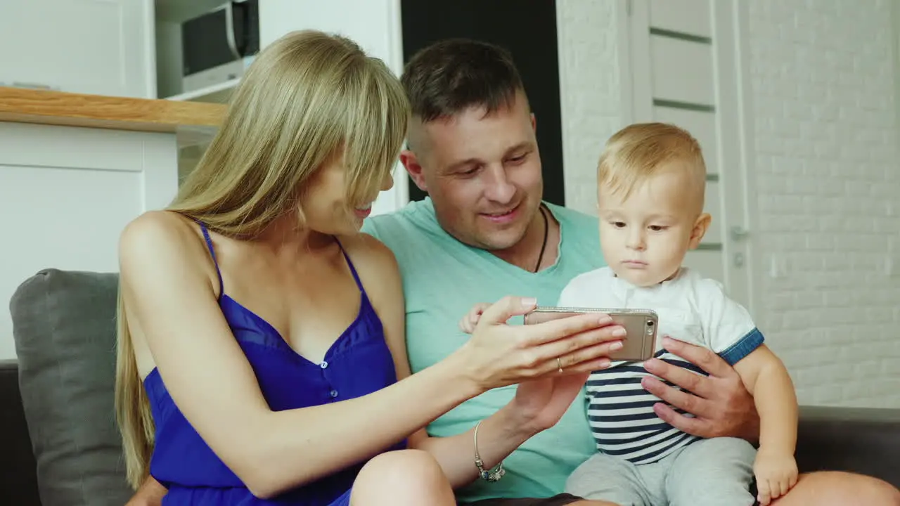 Young Parents Entertain Their Little Son They Show Cartoons On A Smartphone Hd Video