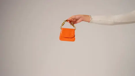 Close Up Of Female Social Media Influencer Producing User Generated Content Holding Out Orange Fashion Handbag 2