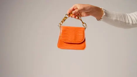 Close Up Of Female Social Media Influencer Producing User Generated Content Holding Out Orange Fashion Handbag 4