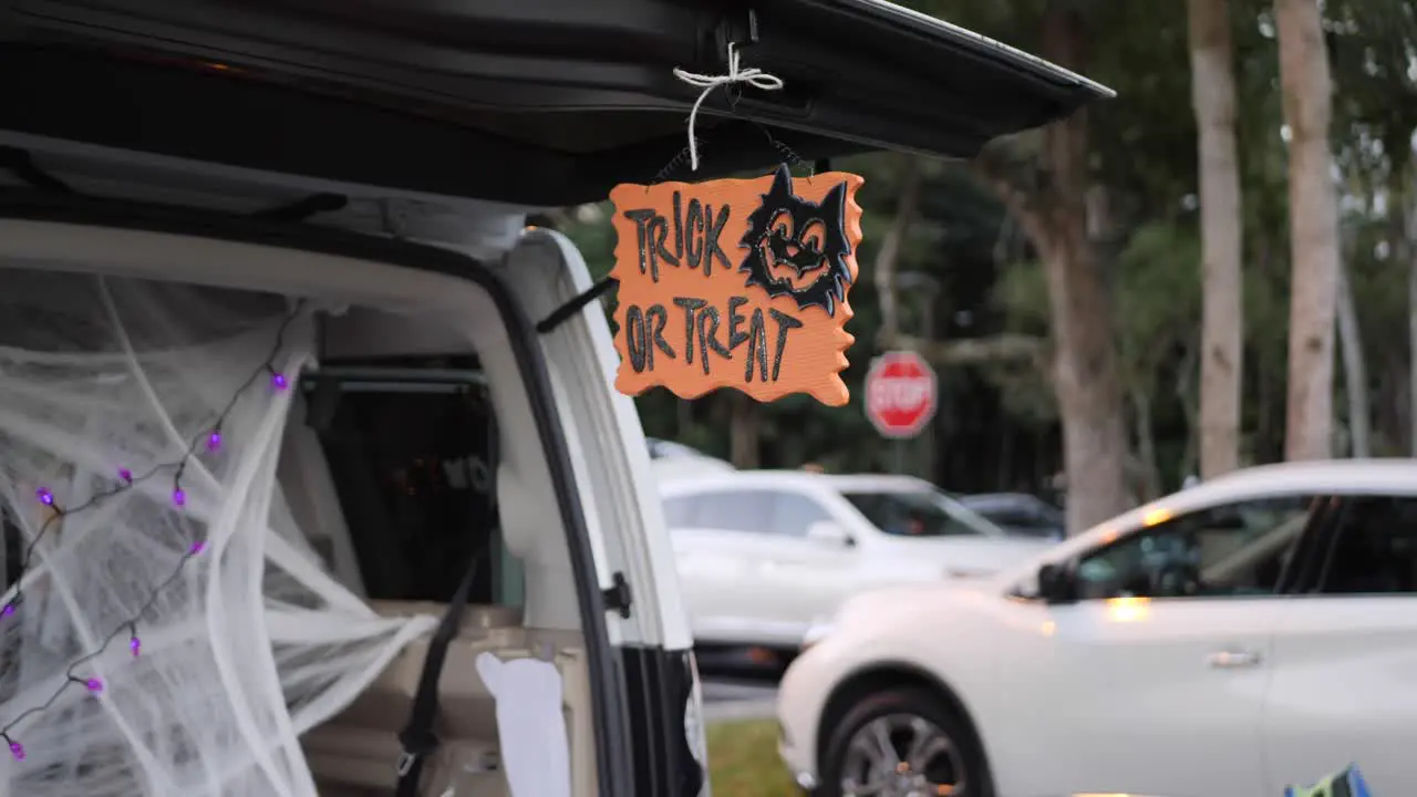 Sign hanging from a cars trunk saying Trick or Treat