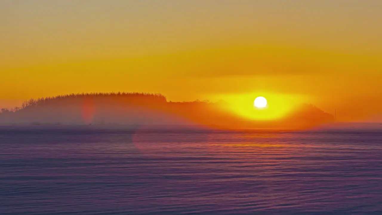 Timelapse shot of golden sunrise over snow covered agricultural fields along rural countryside