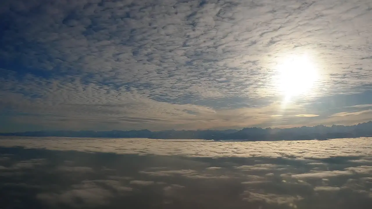 Aerial Still Shot from Plane Window Sun Behind Clouds Blue Sky Late-Day Shadows