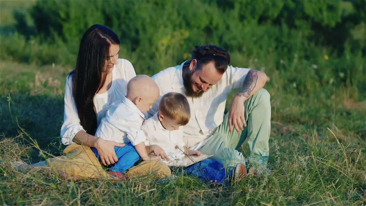 Young Stylishly Dressed Parents Play With Their Sons On A Tablet Outdoor Recreation