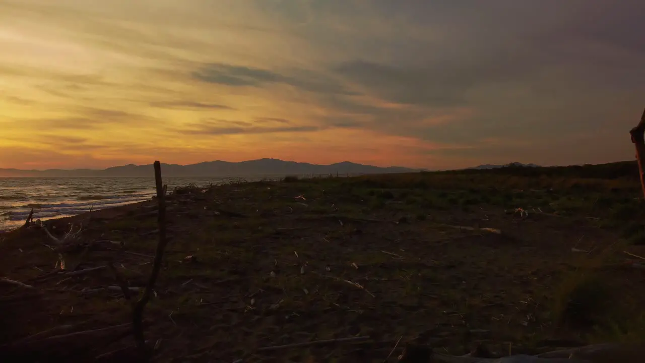 Slow cinematic close up aerial drone footage of the sunset at a sandy beach at the seaside near Alberese in the iconic Maremma nature park in Tuscany Italy with waves islands and a dramatic red sky