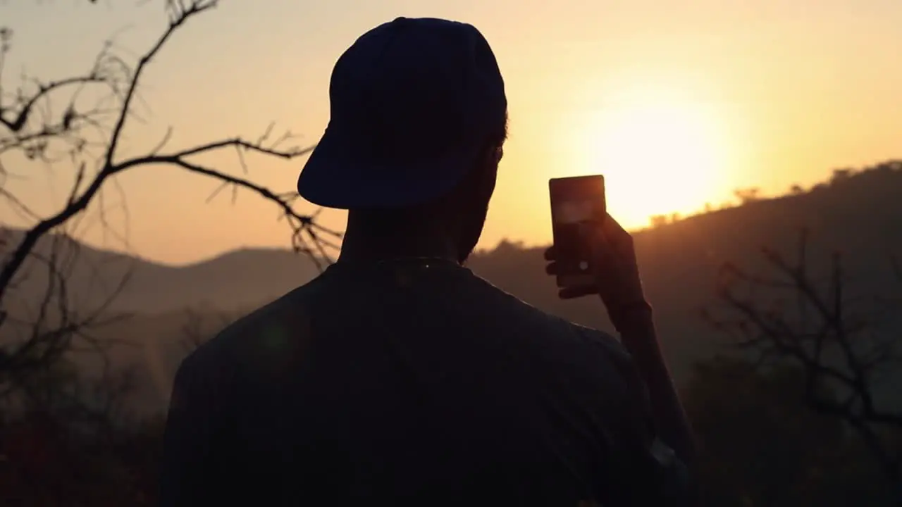 Guy taking photo of sunrise on cell smart phone