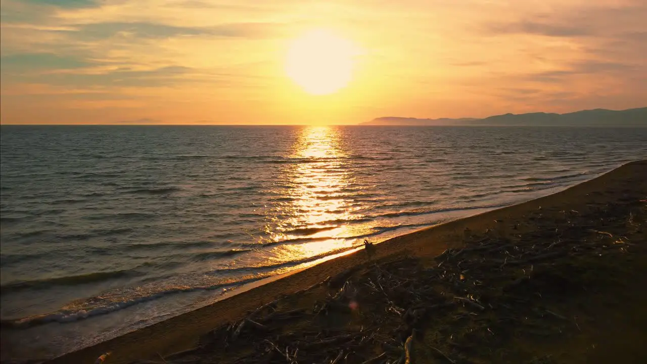 Epic cinematic aerial drone footage of the sunset at a sandy beach at the seaside near Alberese in the iconic Maremma nature park in Tuscany Italy with waves islands and a dramatic red sky