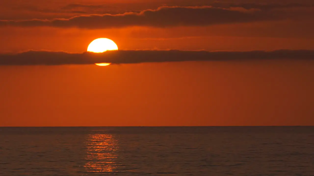 Big orange sun with clouds over ocean at sunrise mediterranean dawn