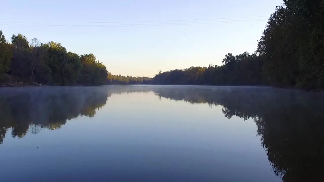 Drone flies over foggy creek on a clear day