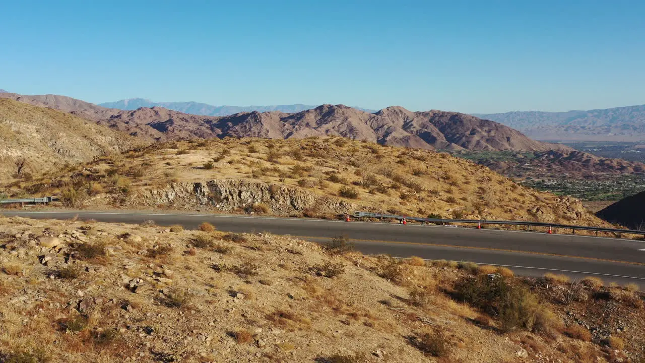 Drone shot flying low over winding desert mountain road to edge of cliff