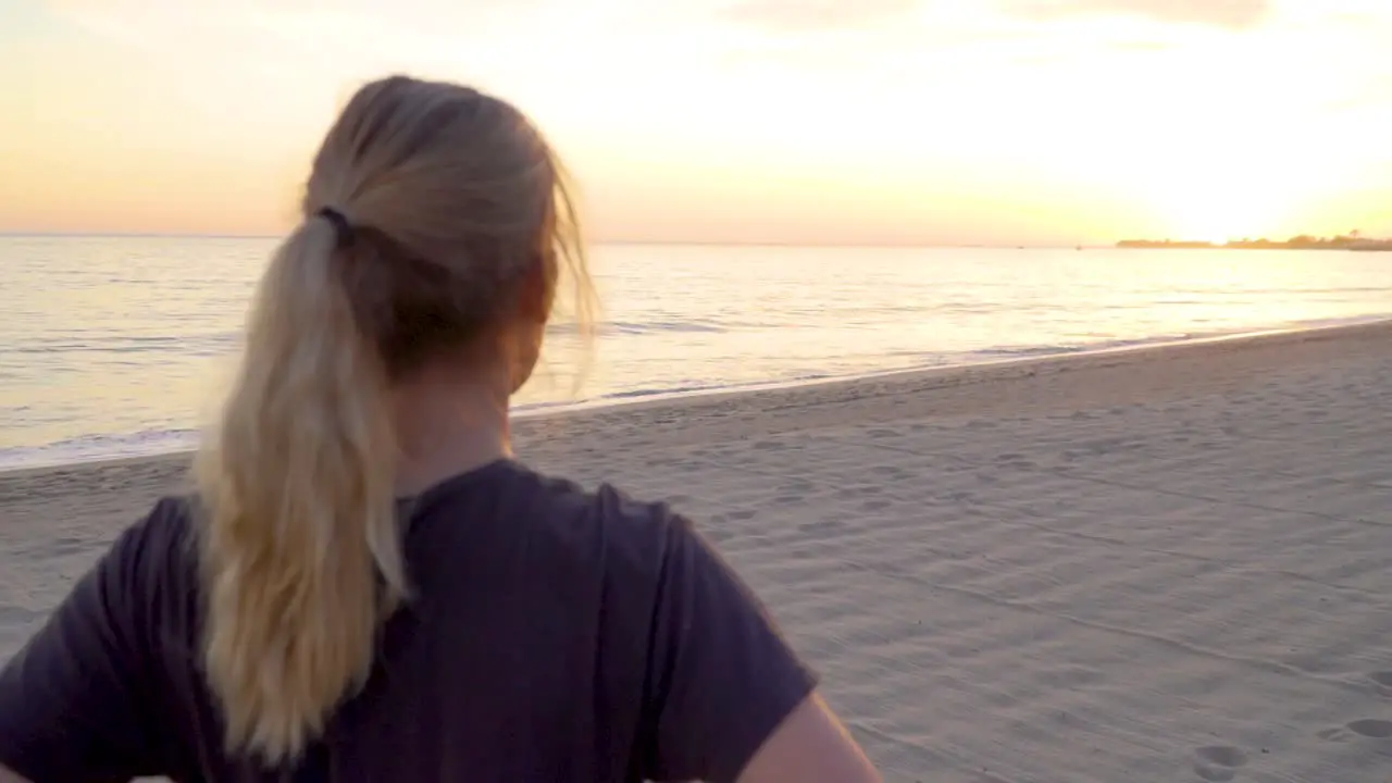 Female looking at the sun setting on empty beach