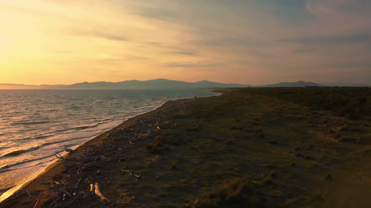 Epic cinematic aerial drone footage of the sunset above a sandy beach at the seaside near Alberese in the iconic Maremma nature park in Tuscany Italy with waves islands and a dramatic red sky