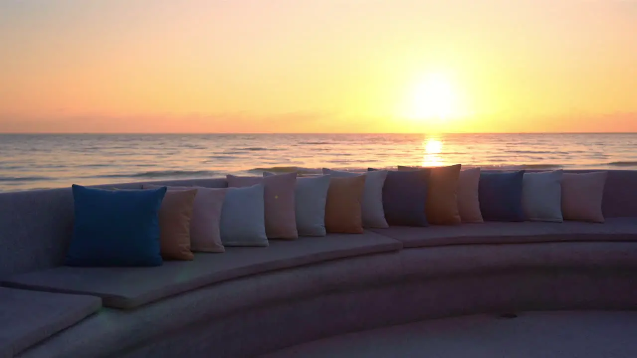 Sunset over sea seen from beach lounge with pillows on seats