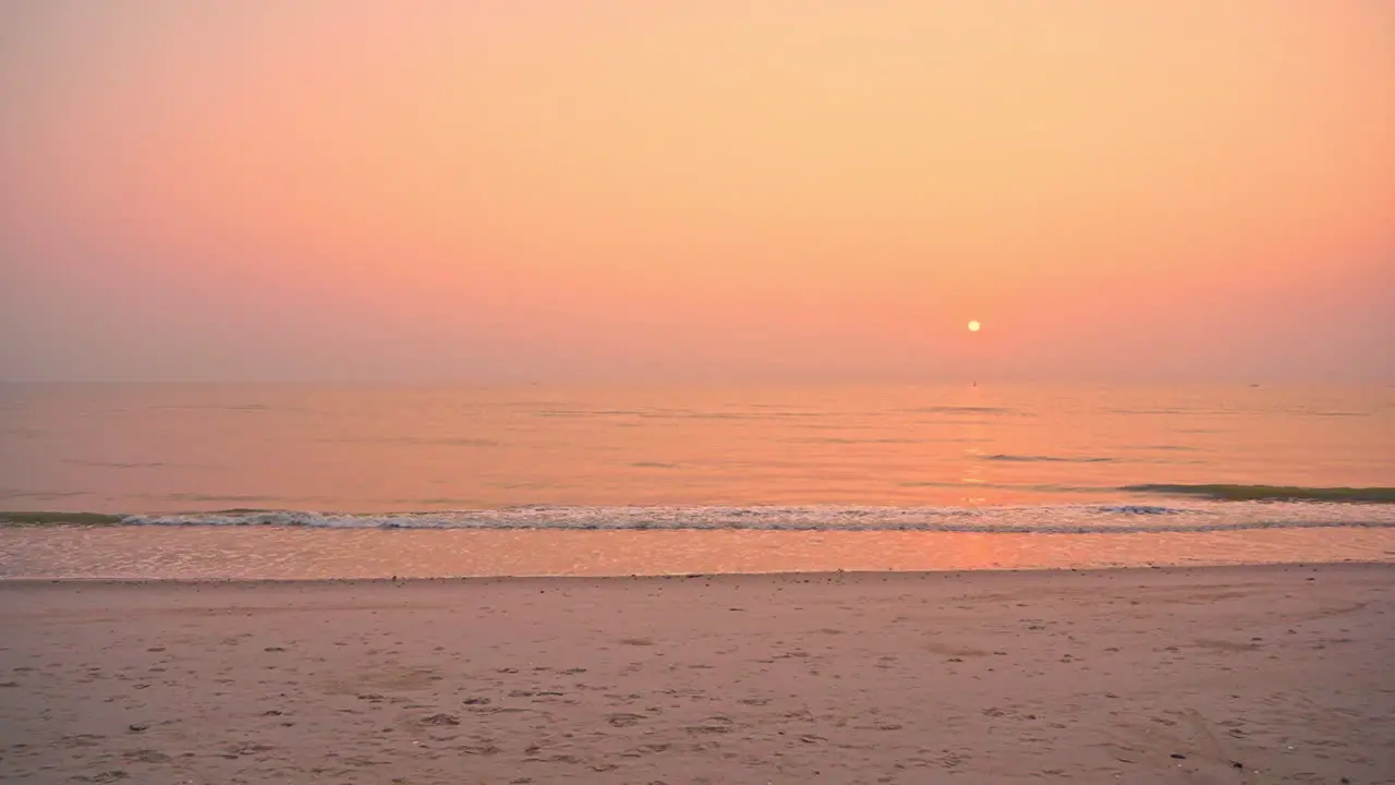 Colorful ocean sunset on the beach with hazy sun in the distance