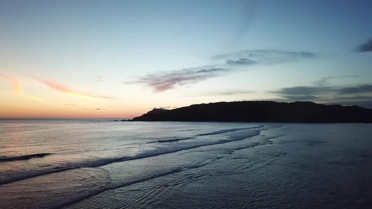 AERIAL 4K Flyover Group of Silhouettes Standing on Edge of Ocean Cliff Sunset