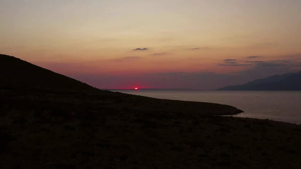 Colorful orange sunset over peaceful Croatian sea ascending aerial